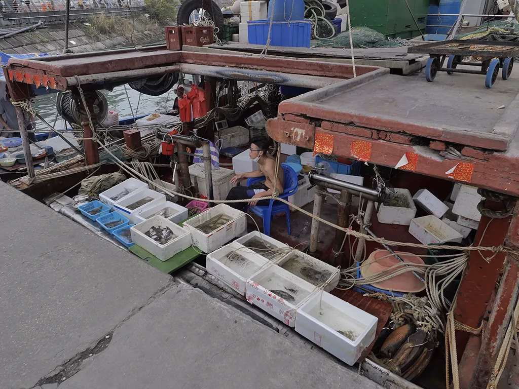 A fisherman selling seafood right on the boat.