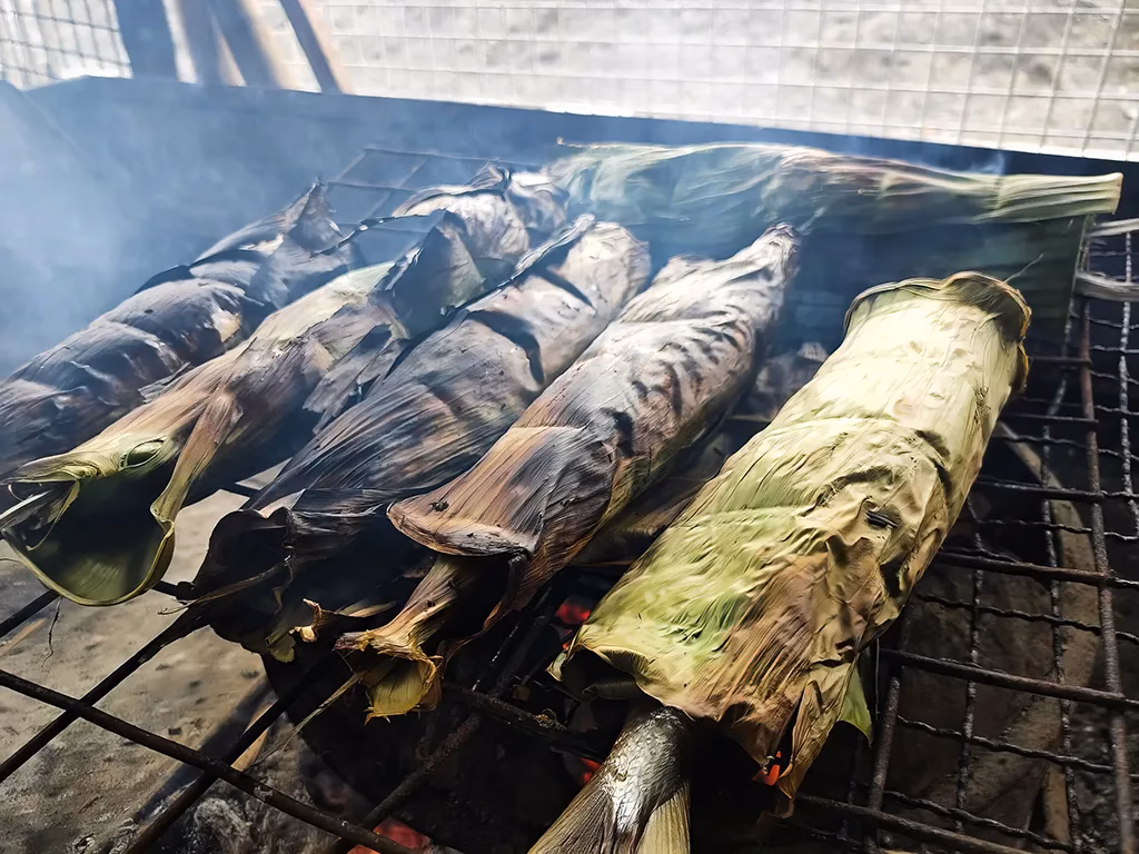 Bangus (Milk Fish) being grilled wrapped in leaves.