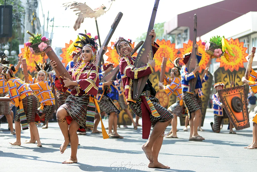 A picture of a very joyous crowd that demonstrated the the joyous essence of this event. Th costumes are very brightly colored and they incorporate recognition of the diverse plant life and agricultural bounty being celebrated.