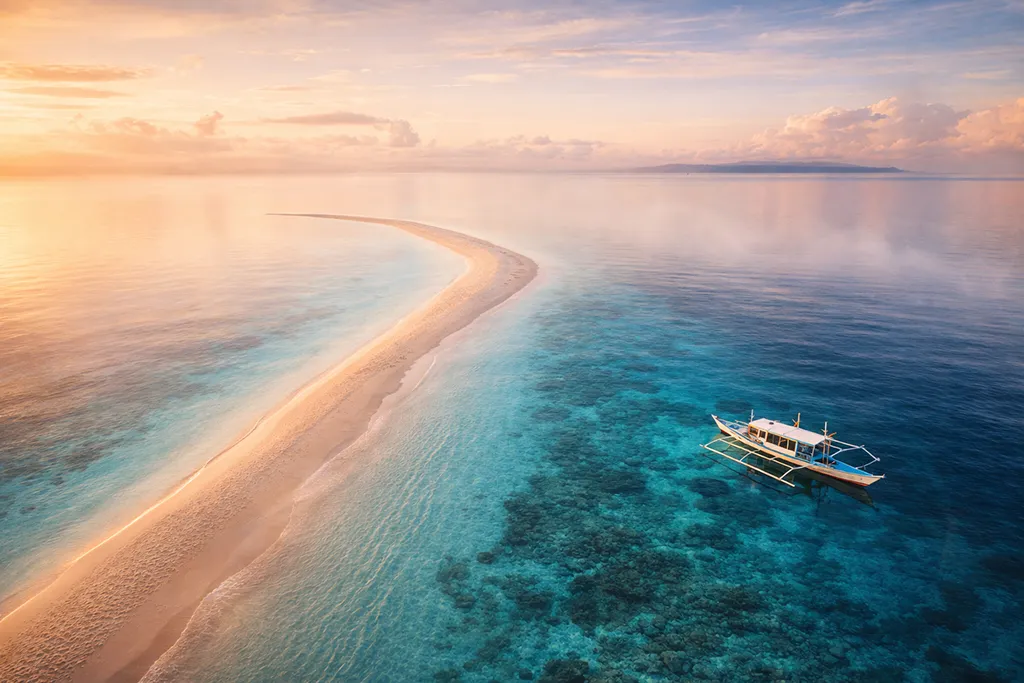 Kalanggaman Island's narrow, white sandbar slicing dramatically through crystal-clear turquoise waters, the vibrant blue sea stretching on both sides.