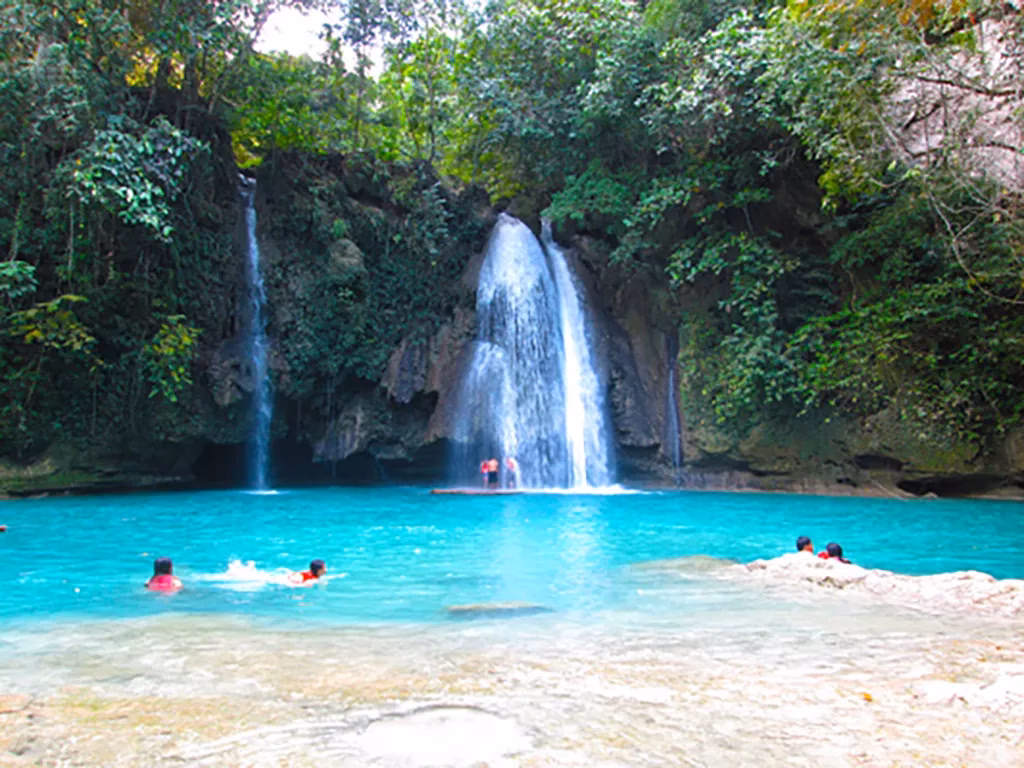 The cascading turquoise waters of Kawasan Falls, framed by lush tropical vegetation.