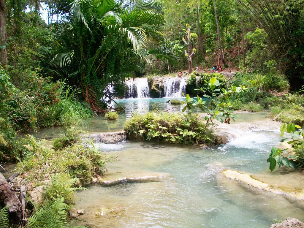 Cambugahay Falls Siquijor Philippines with cascading multi-tier waterfalls, clear turquoise pools, and dense tropical greenery.