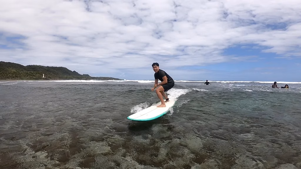 Surfers riding waves at Siargao's Cloud 9, with the iconic wooden boardwalk extending over the water.